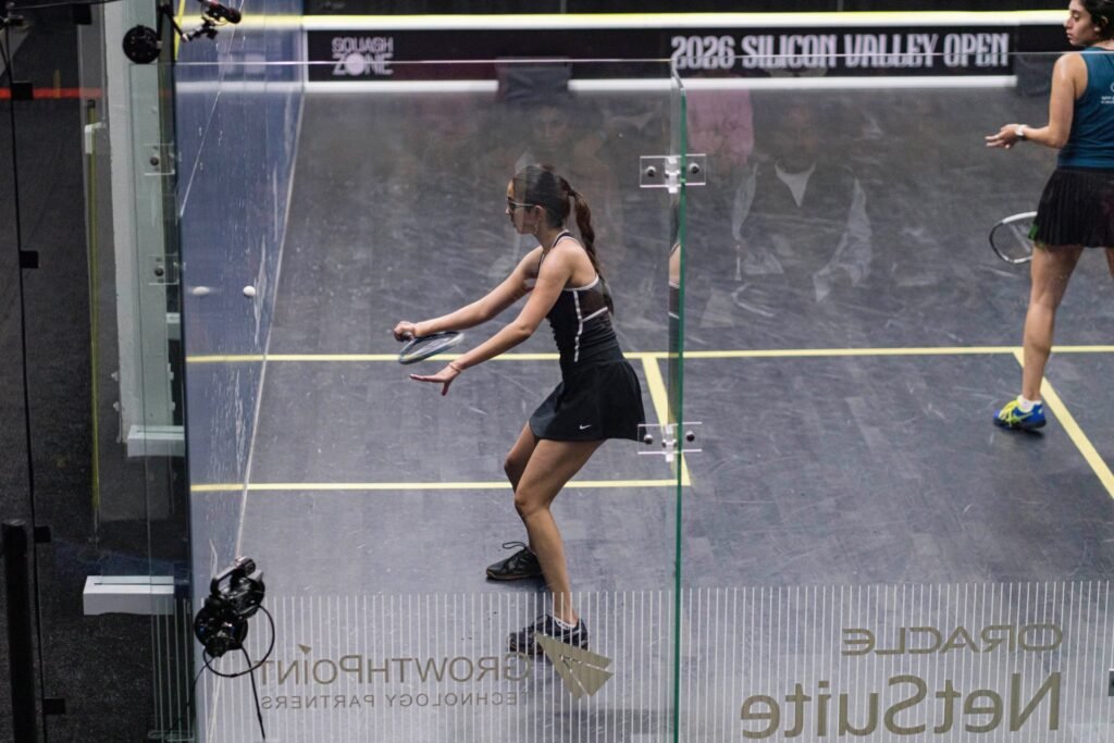 Anahat Singh in a black dress plays a shot on the glass court at the 2026 Silicon Valley Open squash tournament in Redwood City