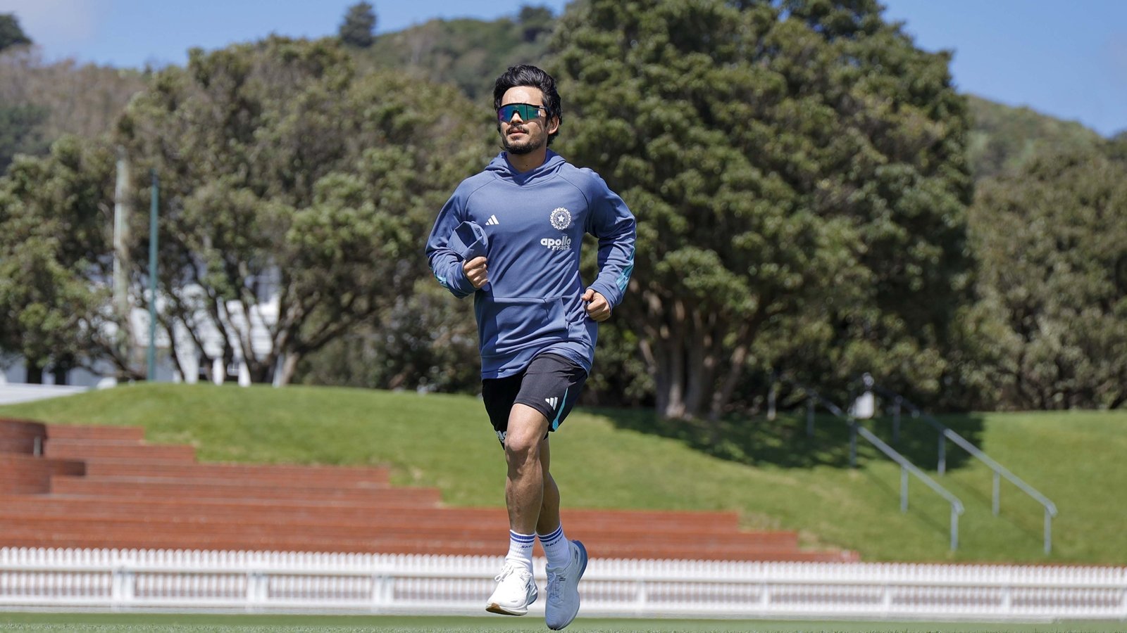 Ishan Kishan, wearing sunglasses and an India training top, runs on the outfield during an India training session in New Zealand