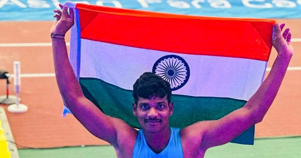 Solairaj Dharmaraj holds the Indian flag above his head on the track after winning the men's long jump gold at the Asian Para Games in Nagoya